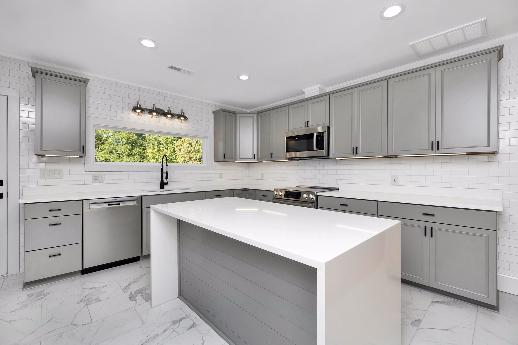 Grey shaker kitchen cabinets with a white waterfall-edge island