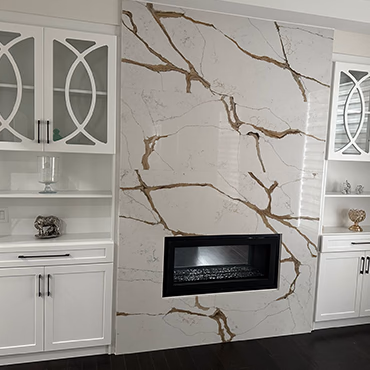 Full-height veined stone surround around a linear fireplace with built-in cabinets